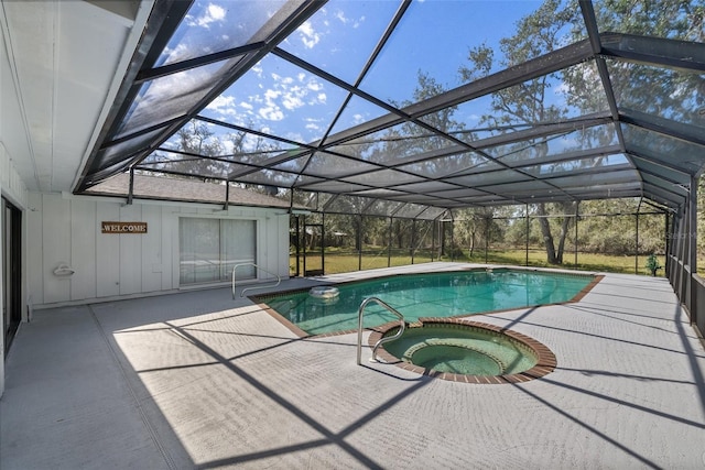 pool with an in ground hot tub, a patio area, and glass enclosure