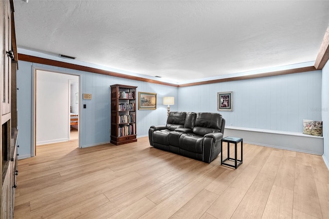 living area featuring visible vents, light wood-style flooring, and a textured ceiling