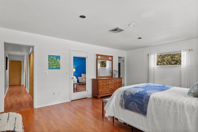 bedroom with baseboards, visible vents, and wood finished floors