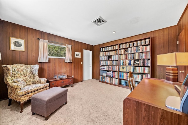 living area with carpet, visible vents, and wooden walls