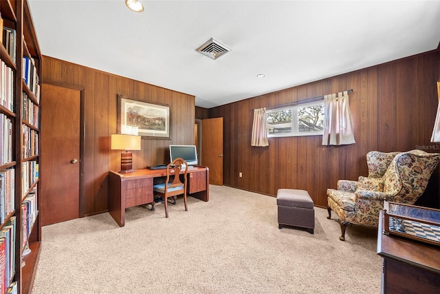 home office featuring light carpet, wood walls, and visible vents