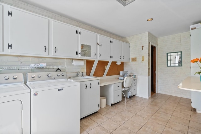 washroom with a sink, light tile patterned floors, washing machine and clothes dryer, and cabinet space