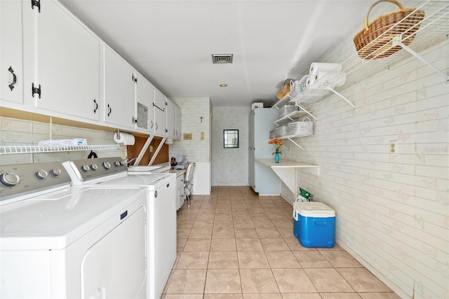 washroom with light tile patterned floors, visible vents, washing machine and dryer, and cabinet space