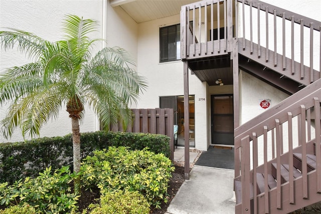 doorway to property featuring fence and stucco siding