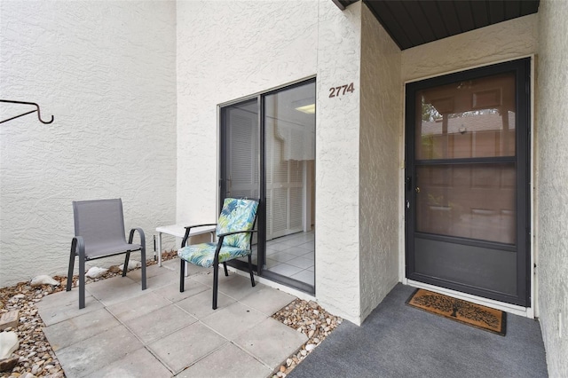 view of exterior entry with a patio area and stucco siding