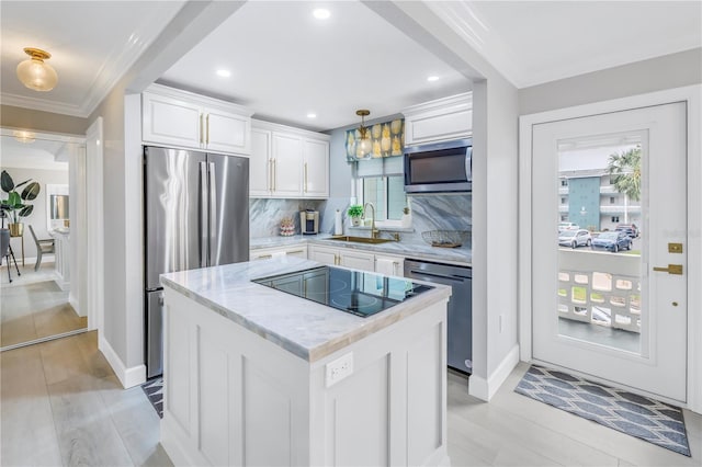 kitchen featuring a sink, white cabinetry, appliances with stainless steel finishes, a center island, and decorative light fixtures