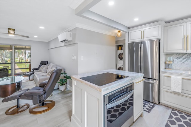 kitchen featuring stacked washer and dryer, appliances with stainless steel finishes, open floor plan, white cabinetry, and a wall mounted air conditioner