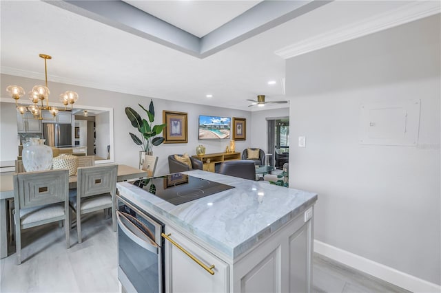 kitchen featuring open floor plan, freestanding refrigerator, light stone countertops, black electric stovetop, and pendant lighting