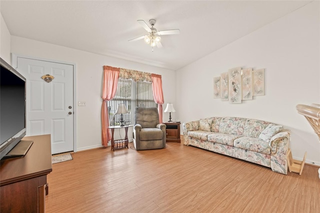 living area featuring baseboards, a ceiling fan, and wood finished floors