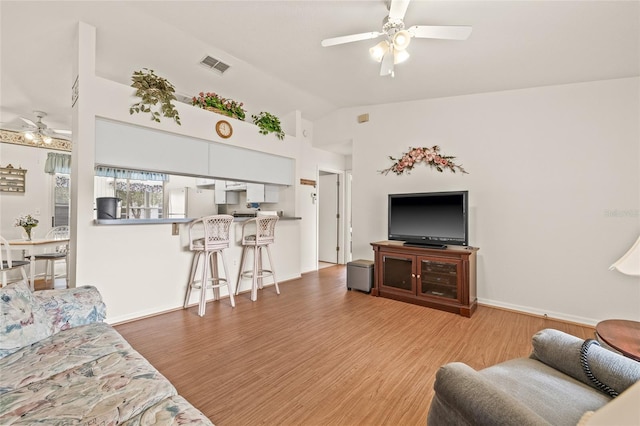 living area featuring baseboards, visible vents, a ceiling fan, lofted ceiling, and light wood-type flooring