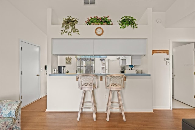 kitchen with light wood-type flooring, visible vents, and white cabinets