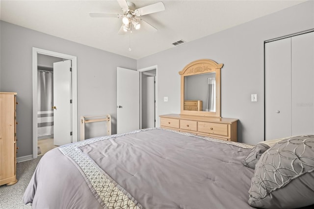 carpeted bedroom with a closet, visible vents, a ceiling fan, ensuite bath, and baseboards