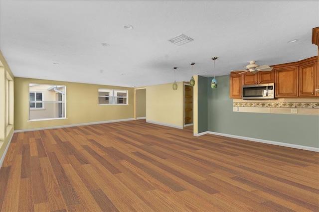 unfurnished living room featuring visible vents, ceiling fan, and baseboards