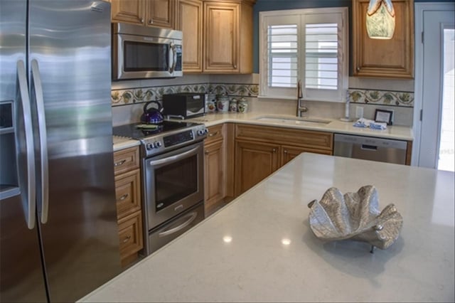 kitchen featuring tasteful backsplash, appliances with stainless steel finishes, a sink, and brown cabinets