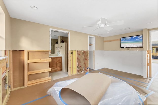 bedroom with freestanding refrigerator, connected bathroom, and a ceiling fan