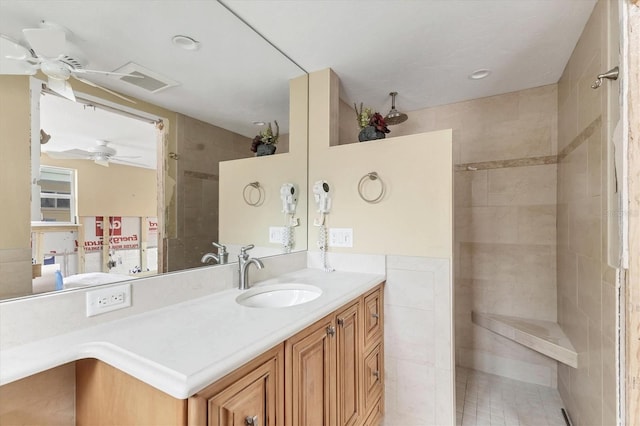 bathroom featuring visible vents, tile walls, vanity, a ceiling fan, and walk in shower