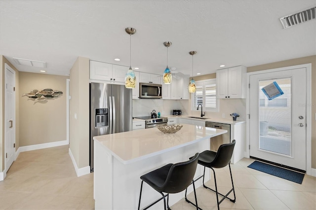 6140 Midnight Pass Rd Unit A10, Sarasota, FL 34242 - kitchen with appliances with stainless steel finishes, light countertops, white cabinetry, a center island, and a kitchen breakfast bar