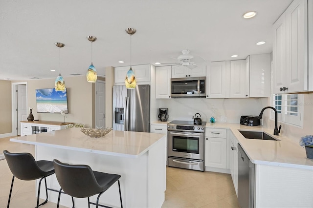 6140 Midnight Pass Rd Unit A10, Sarasota, FL 34242 - kitchen featuring stainless steel appliances, white cabinetry, a kitchen island, a kitchen breakfast bar, and light countertops