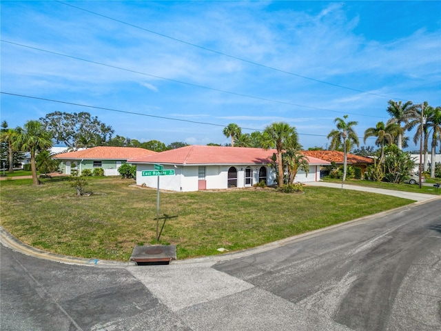 single story home with a garage, driveway, a tile roof, and a front lawn