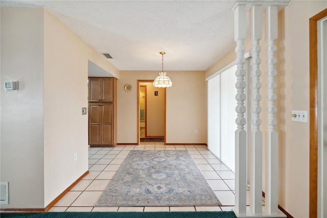 unfurnished dining area featuring light tile patterned floors, a textured ceiling, visible vents, and baseboards