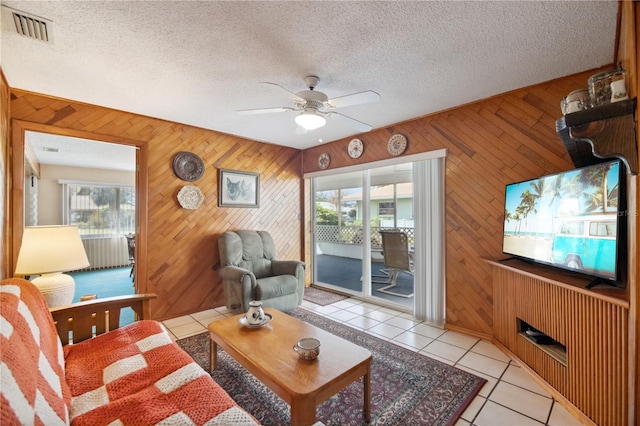 living room featuring a textured ceiling, ceiling fan, light tile patterned flooring, and visible vents