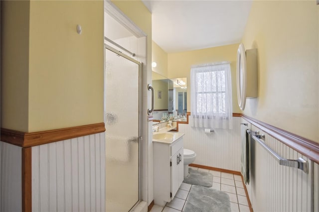 full bath featuring a wainscoted wall, toilet, vanity, a shower stall, and tile patterned floors