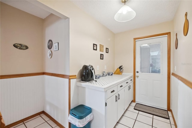 doorway to outside with light tile patterned flooring and a textured ceiling