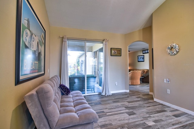 sitting room featuring arched walkways, baseboards, and wood finished floors