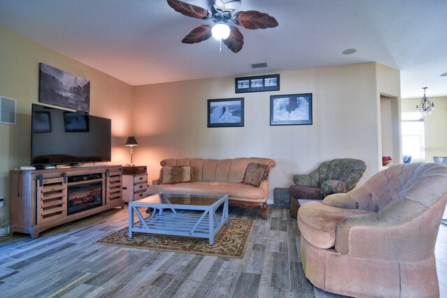 living room with ceiling fan with notable chandelier, wood finished floors, and visible vents