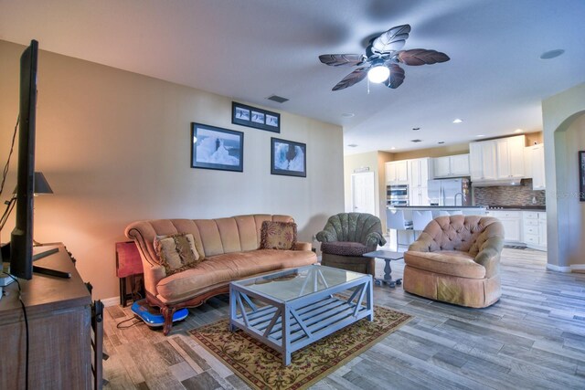 living room with baseboards, light wood-type flooring, visible vents, and a ceiling fan