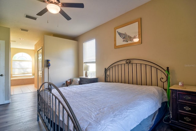 bedroom with a ceiling fan, visible vents, wood finished floors, and ensuite bathroom