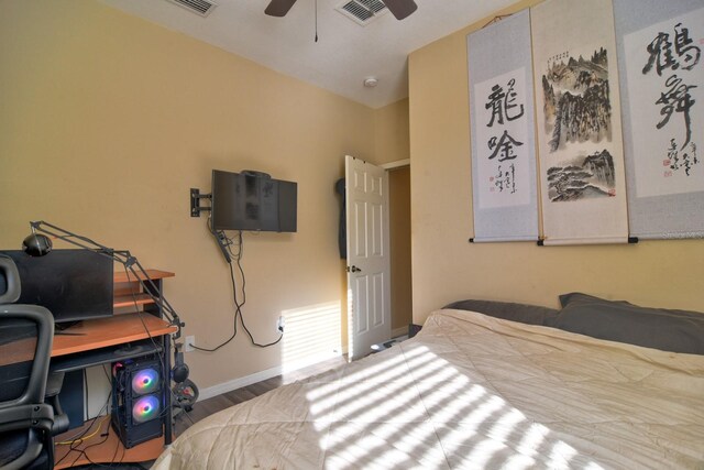 bedroom with a ceiling fan, visible vents, baseboards, and wood finished floors