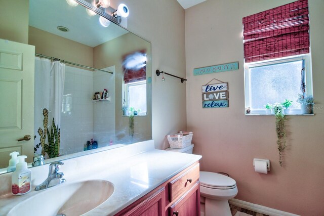 bathroom featuring curtained shower, baseboards, vanity, and toilet