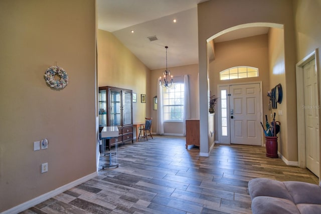 foyer entrance with dark wood finished floors, baseboards, and an inviting chandelier