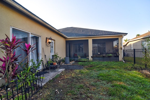 back of house with fence, a lawn, and stucco siding