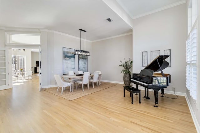 dining area with baseboards, visible vents, crown molding, and light wood finished floors