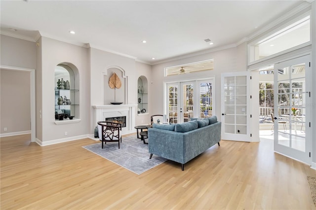 living room featuring light wood-type flooring, a fireplace, baseboards, and french doors