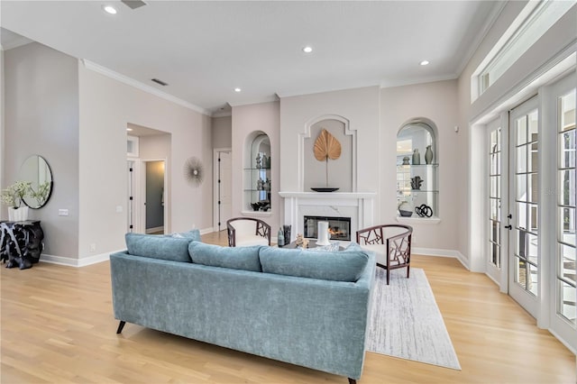 living room featuring crown molding, light wood finished floors, a premium fireplace, and baseboards