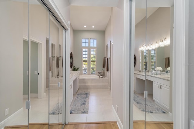 full bath featuring baseboards, vanity, a bath, and tile patterned floors