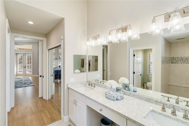 ensuite bathroom with french doors, visible vents, a sink, and toilet