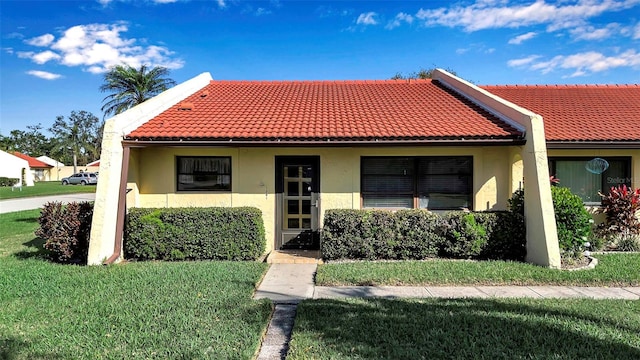 view of front facade with a tile roof, a front lawn, and stucco siding