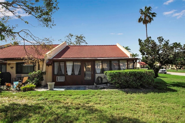 back of house featuring a tile roof, a yard, and stucco siding