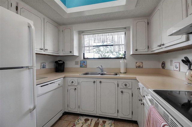 kitchen featuring white appliances, light countertops, a sink, and white cabinets