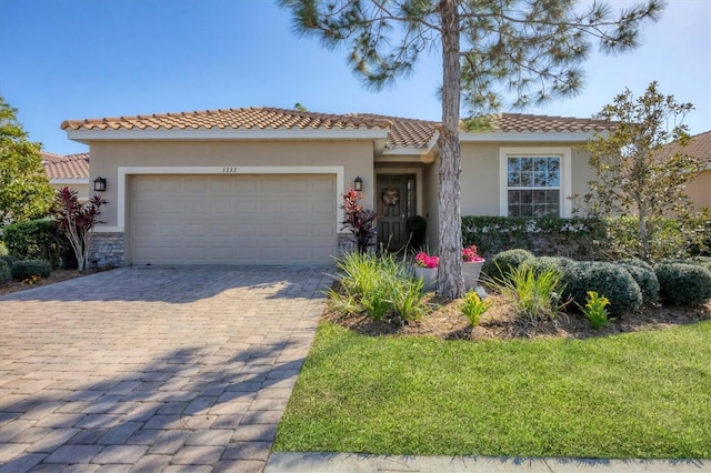 mediterranean / spanish house featuring an attached garage, a front lawn, decorative driveway, and stucco siding