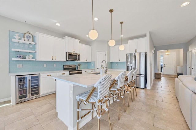 kitchen featuring white cabinetry, appliances with stainless steel finishes, beverage cooler, and a sink