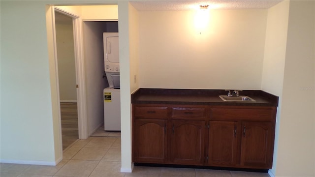 bathroom with a sink, stacked washer / drying machine, a textured ceiling, and tile patterned flooring