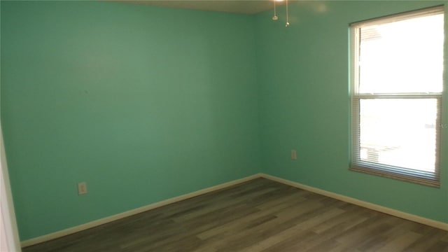 unfurnished room featuring baseboards and dark wood-style flooring