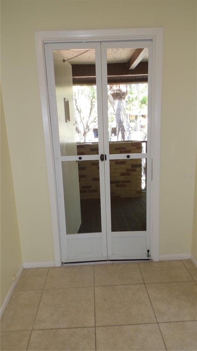 doorway with tile patterned floors and baseboards