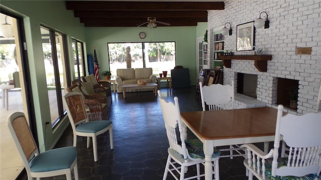 dining space featuring beamed ceiling, a brick fireplace, and ceiling fan