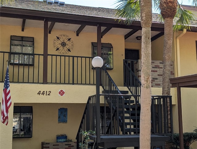 exterior space featuring stucco siding and a shingled roof